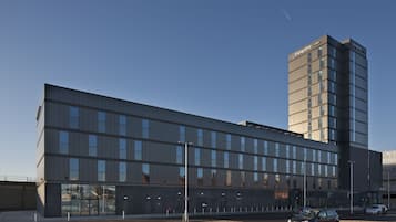 Un hôtel moderne, avec une grande enseigne « Hampton » bien visible sur le toit.