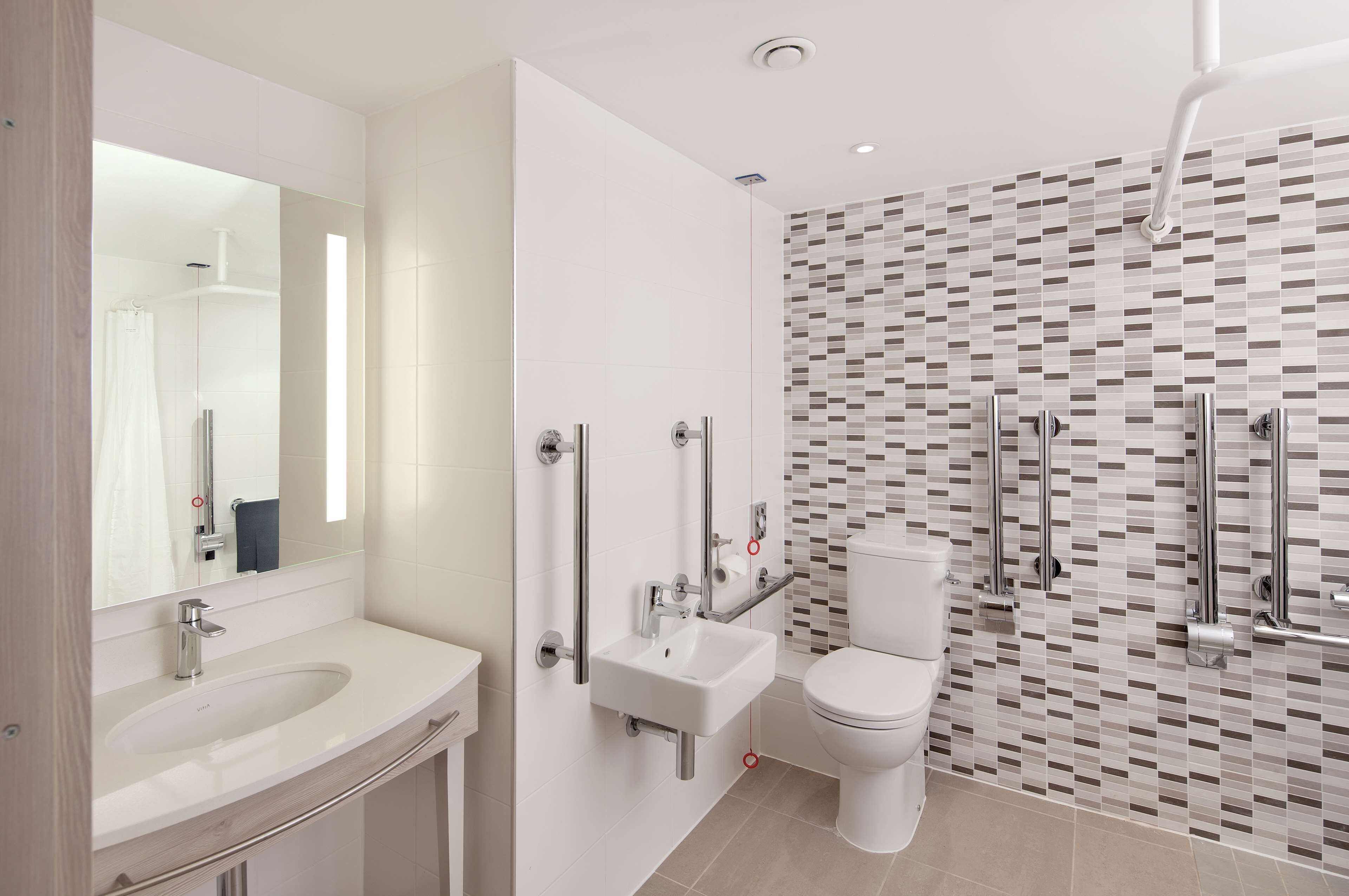 A modern bathroom with a white sink, mirror, and toilet.