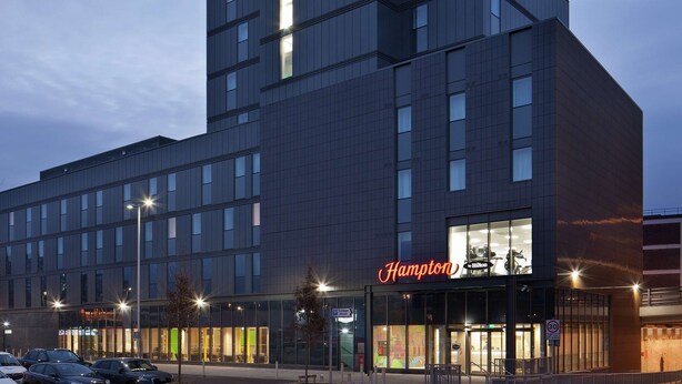 A modern hotel building with a prominent "Hampton" sign on the top and another on the lower facade. - Hampton by Hilton Leeds City Centre (Leeds)