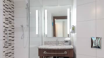 Un baño moderno con ducha de vidrio, lavamanos de granito y un espejo.
