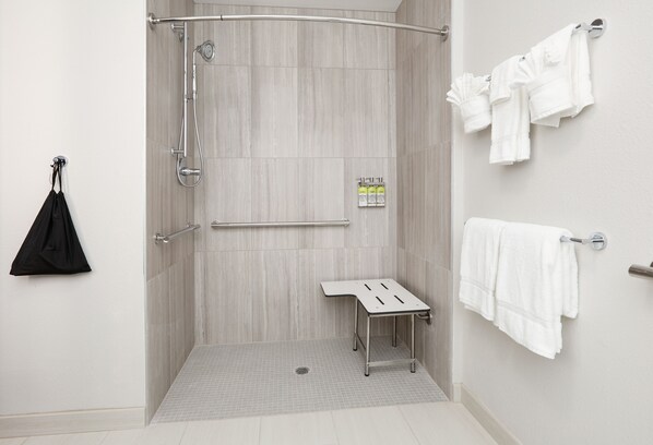 Un espace douche moderne doté d’une porte en verre, d’un porte-serviettes et d’une petite table.