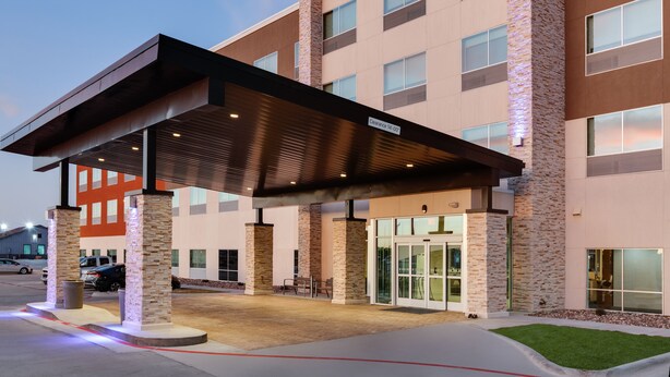 A hotel entrance with a covered walkway, stone pillars, and a glass door entrance. - Holiday Inn Express Kermit by IHG (Kermit)