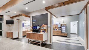 A modern coffee shop interior with a coffee bar, seating area, and a digital menu display. - Holiday Inn Express Kermit by IHG (Kermit)