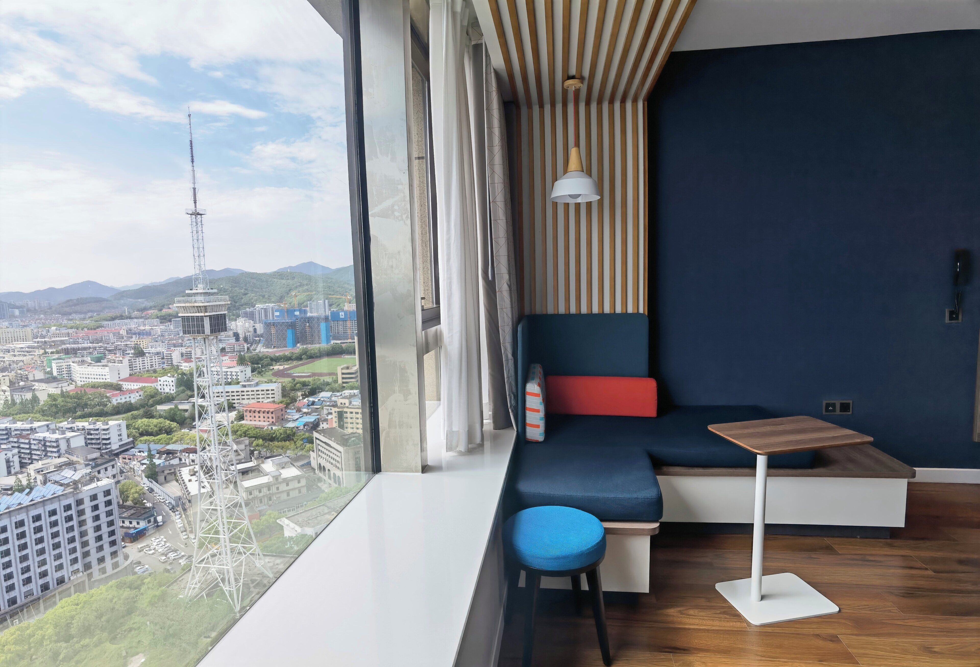 Una habitación moderna con un ventanal grande, un sofá, una mesita y una silla.