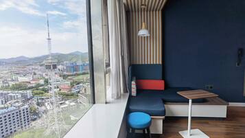 Una habitación moderna con un ventanal grande, un sofá, una mesita y una silla.
