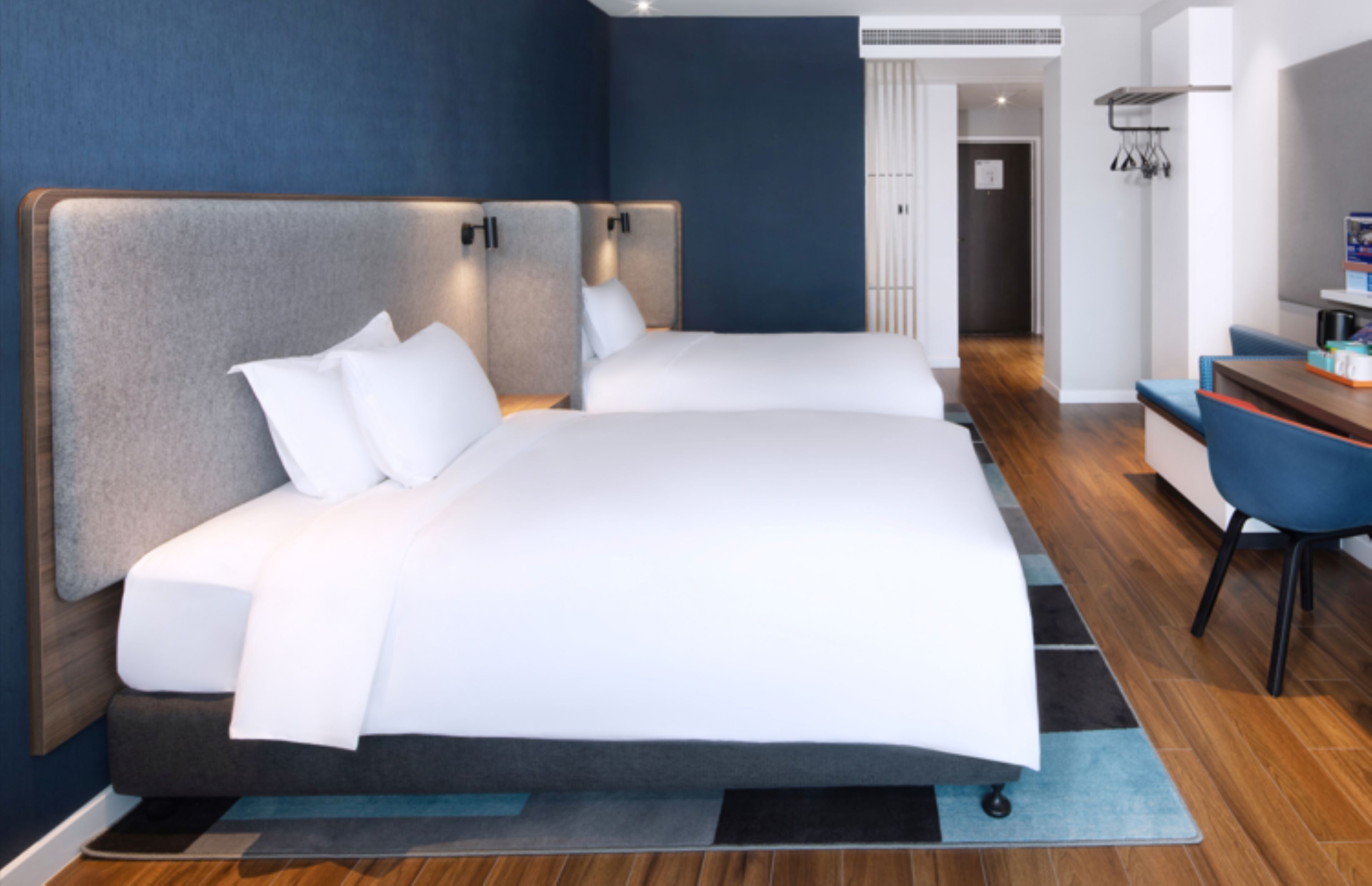 Una habitación de hotel moderna con dos camas, un escritorio y una silla.