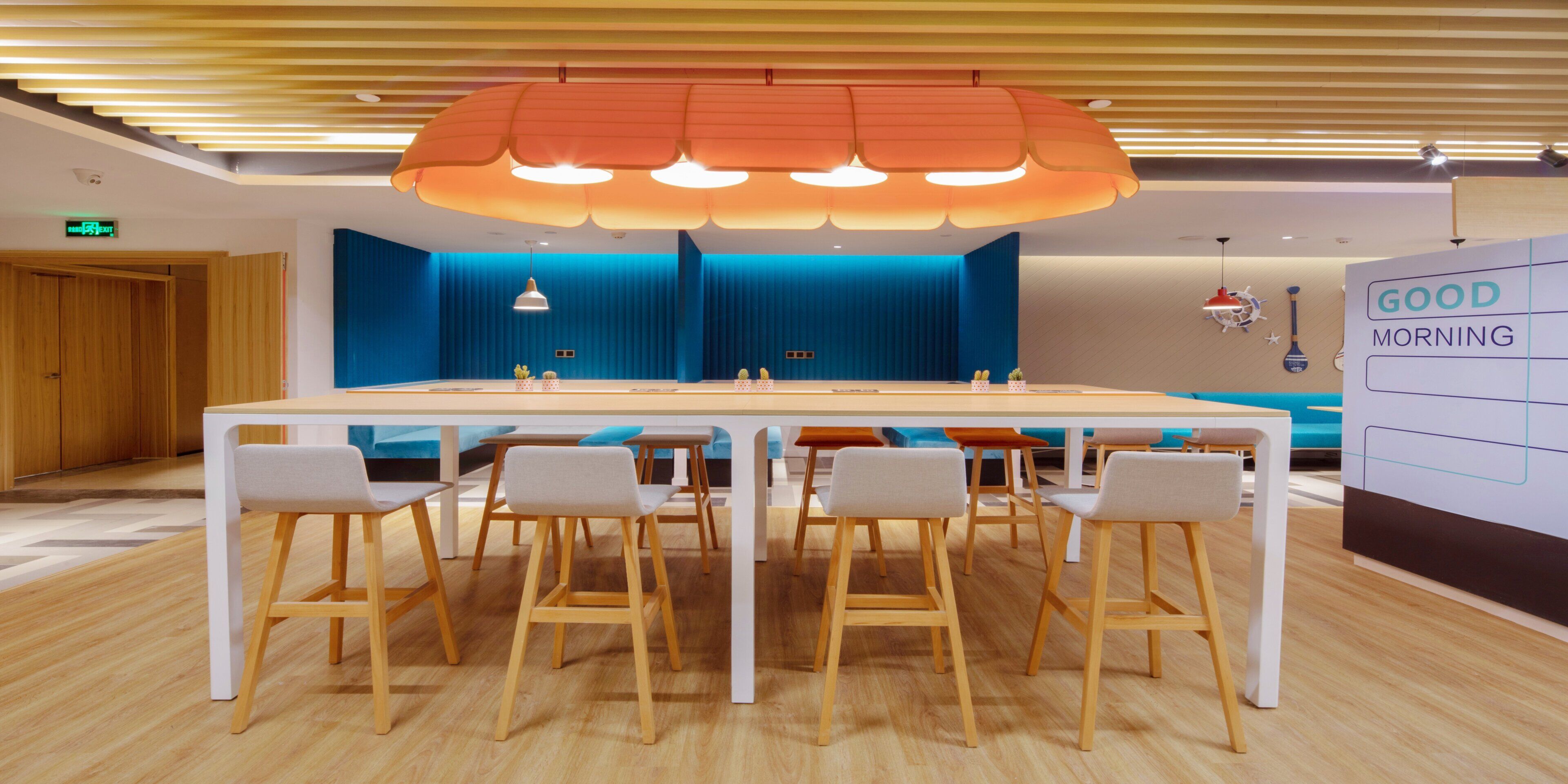A modern meeting room with a long table, chairs, and a ceiling light fixture.