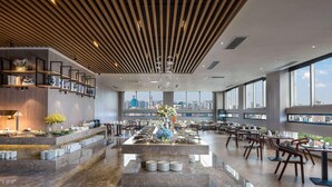 Un comedor moderno con un bufé central, techos altos y amplios ventanales con vistas a la ciudad.