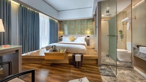 Una habitación de hotel moderna con cama, mesita de noche, lámpara y vistas al baño.