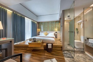 A modern hotel room with a bed, bedside table, lamp, and a view of the bathroom.