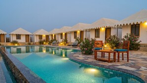 A poolside area with a pool, lounge chairs, and a row of tents. - Style Desert Camp Jaisalmer (Jaisalmer)