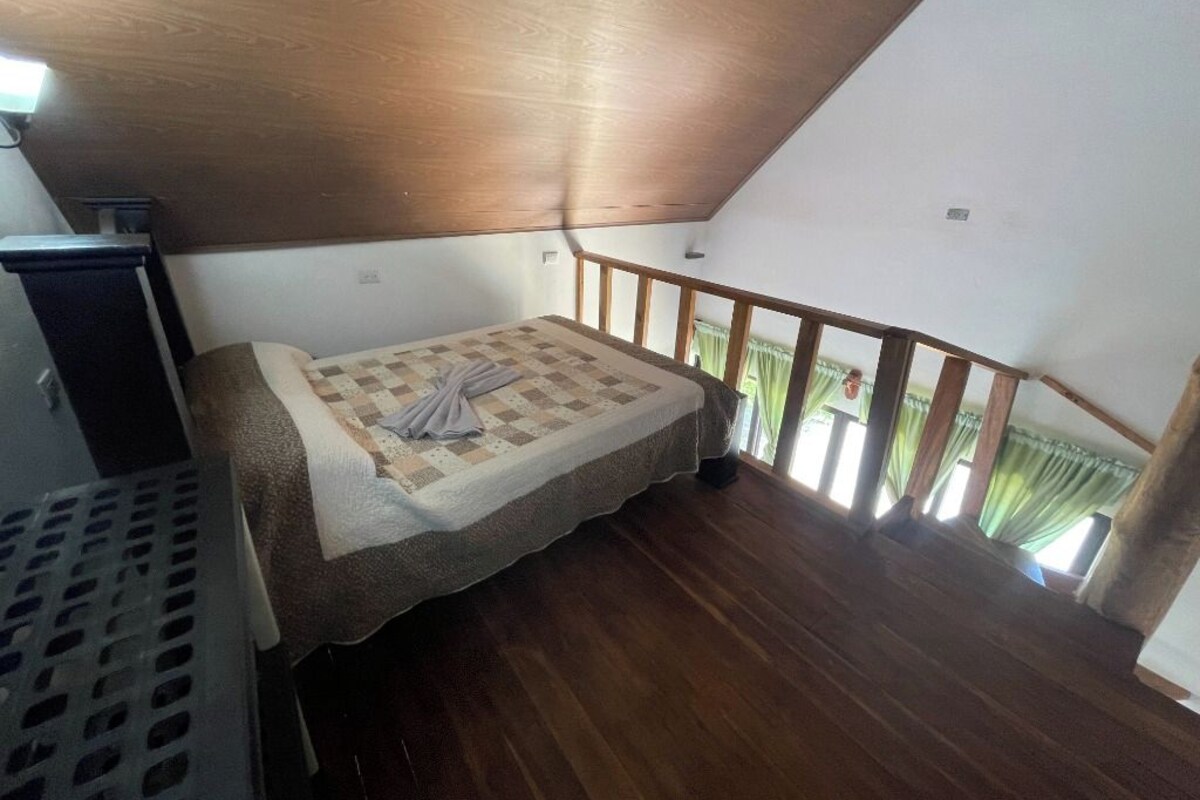 A small, single-bed room with a wooden ceiling and a balcony with a wooden railing.