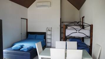 A bedroom with a single bed, a bunk bed, a table with chairs, and a ceiling fan.