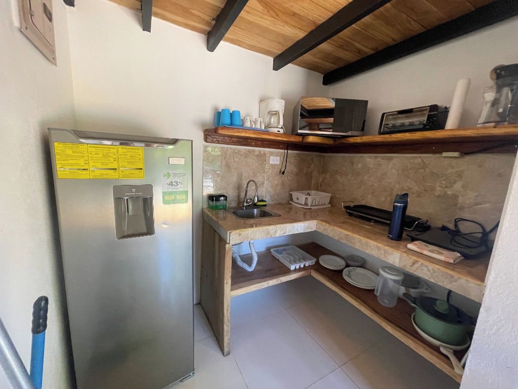 A compact kitchen with a stainless steel refrigerator, a microwave, and a sink.