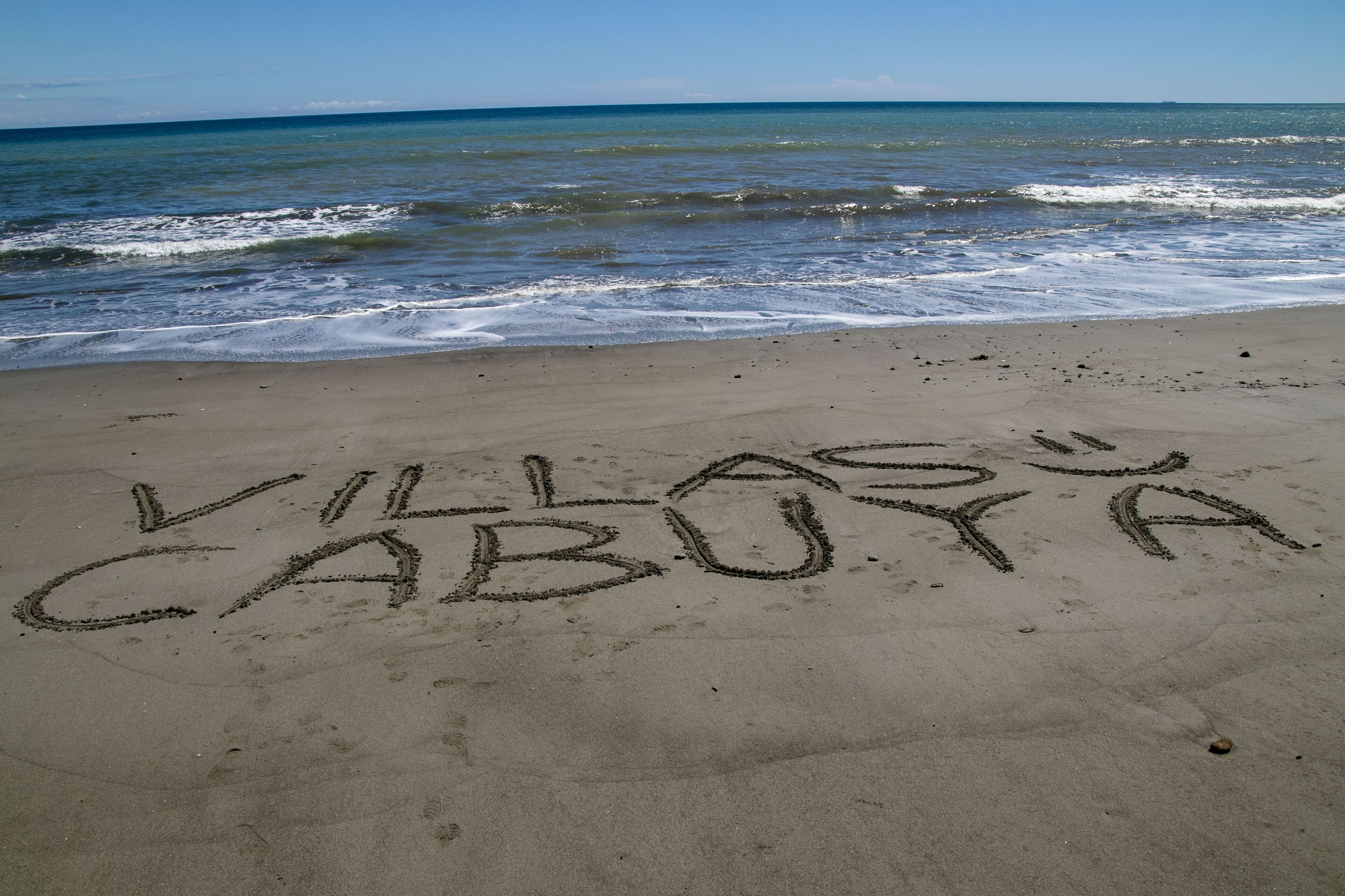 A beach with the words "VILLAS CABOYA" written in the sand.