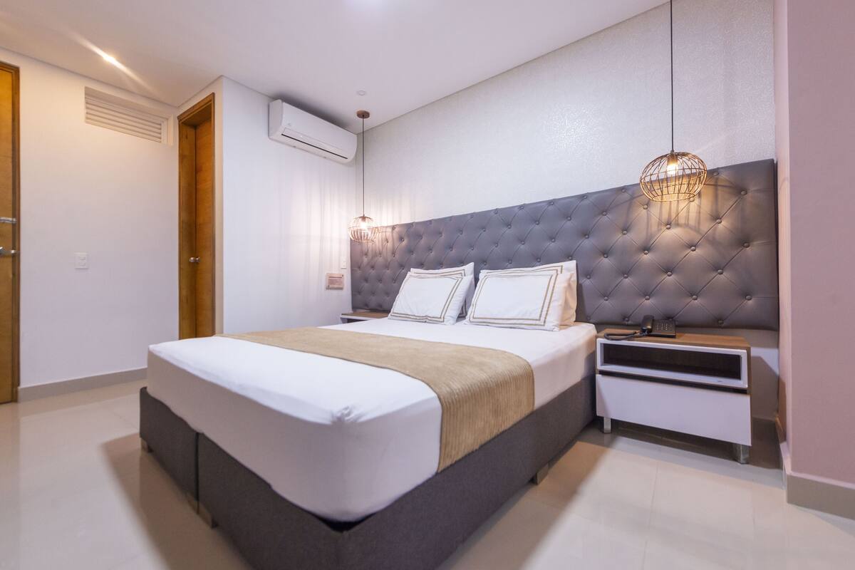 A modern bedroom with a tufted headboard, a bedside table with a lamp, and a built-in wardrobe.