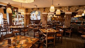 Un restaurant avec des tables et des chaises en bois, ainsi que des luminaires suspendus.