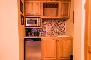 A compact kitchen with wooden cabinets, a built-in microwave, and a stainless steel refrigerator. - Vacation Rentals María Bonita (Ciudad Juárez)