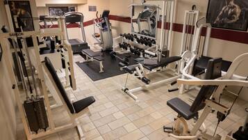 Un gimnasio con diversas máquinas de ejercicio, bancos y mancuernas.