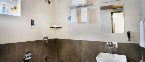 Un baño moderno con techo de madera, un lavabo blanco, un espejo grande y una zona de ducha.