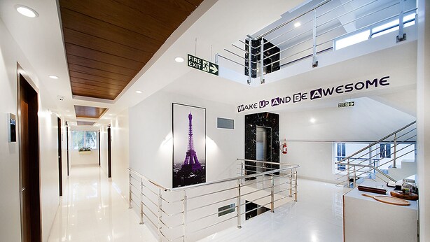 A modern hotel lobby with a glass railing, a poster of the Eiffel Tower, and a sign that says "MAKE UP AND BE AWESOME". - Raj Residency (Bengaluru)