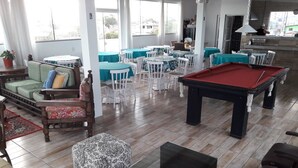 Un grand espace intérieur comprenant une table de billard, plusieurs tables et chaises, ainsi qu’un canapé.