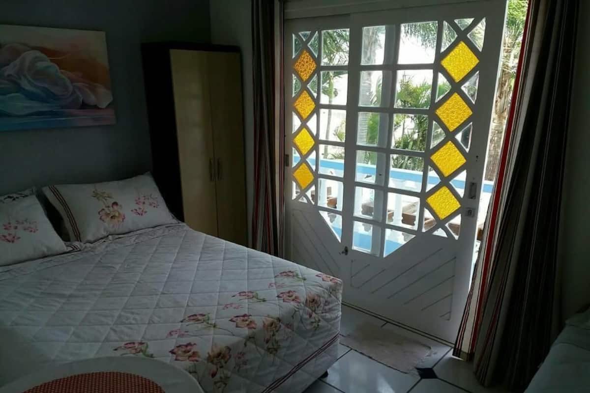 Un dormitorio con cama, armario y vistas a través de una puerta con diseño geométrico.