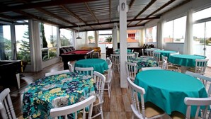 Un espace de restauration en plein air avec des tables rondes recouvertes de nappes vertes et des chaises blanches.