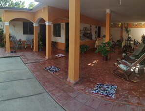 A covered outdoor area with tiled flooring, potted plants, and outdoor furniture. - Casa Naturaleza Felix y Zoilita (Ciénaga de Zapata)