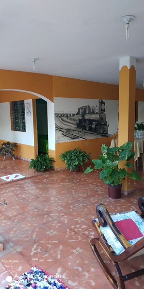 A room with a tiled floor, a mural of a train on the wall, and several potted plants. - Casa Naturaleza Felix y Zoilita (Ciénaga de Zapata)