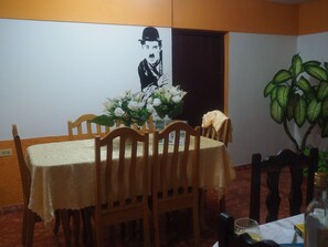 A dining area with a table set for four, surrounded by wooden chairs. A vase with white flowers is on the table, and a potted plant is to the right. - Casa Naturaleza Felix y Zoilita (Ciénaga de Zapata)