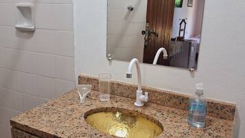 Un baño con encimera de granito, un lavamanos con grifo, un espejo y un dispensador de jabón.