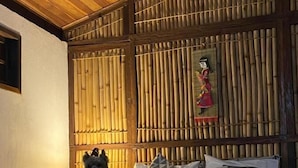 A bed with a white bedspread and pillows, a wooden headboard with vertical slats, and a small dog sitting on the bed. - Chalé na Montanha (Cunha)