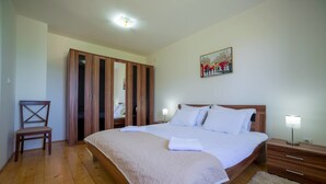 A bedroom with a large bed, wooden wardrobe, a chair, bedside tables, and a painting on the wall. - Villa SOA (Razvršje)