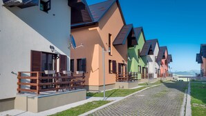 A row of colorful houses with outdoor seating and a paved walkway. - Villa SOA (Razvršje)