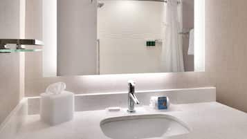 A modern bathroom with a large mirror, a white sink, and a glass shelf.