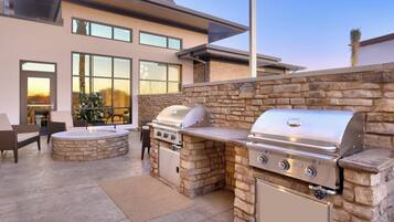 Una zona de cocina al aire libre con paredes de piedra, una parrilla y un hogar.
