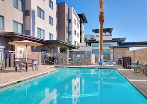 Un hotel moderno con piscina, zona de estar al aire libre y una palmera.