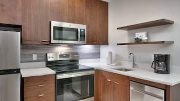 A modern kitchen with stainless steel appliances, wooden cabinets, and a white countertop.