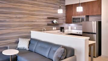 A modern kitchen with a built-in microwave, stainless steel refrigerator, and wooden cabinets.