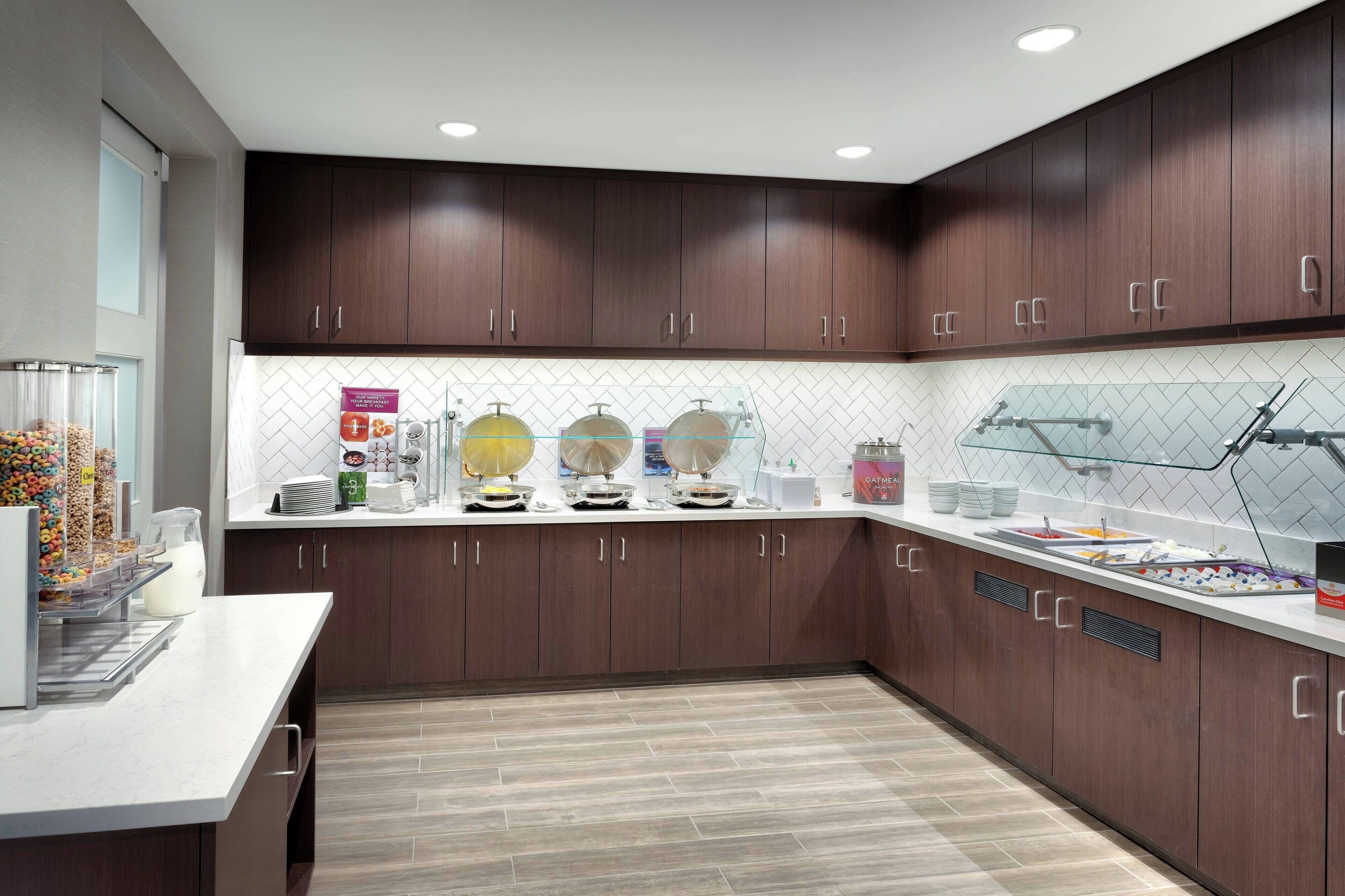A modern kitchen with dark wood cabinets, a white countertop, and a tiled backsplash.