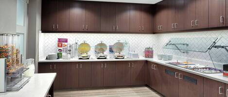 A modern kitchen with dark wood cabinets, a white countertop, and a tiled backsplash.