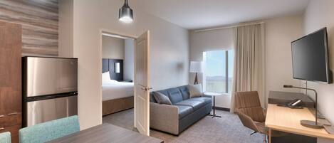Une chambre d’hôtel comprenant un lit, un bureau, une chaise, un canapé, une télévision et un coin repas.
