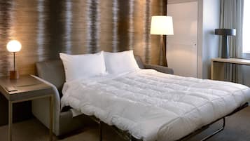 A hotel room with a large bed, a bedside table with a lamp, and a wall-mounted headboard.