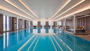 A large indoor swimming pool with clear blue water, surrounded by seating areas and large windows. - Sheraton Shanghai Fengxian (Shanghai)