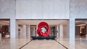 A modern lobby with a central red sculpture, marble flooring, and a geometric ceiling design. - Sheraton Shanghai Fengxian (Shanghai)