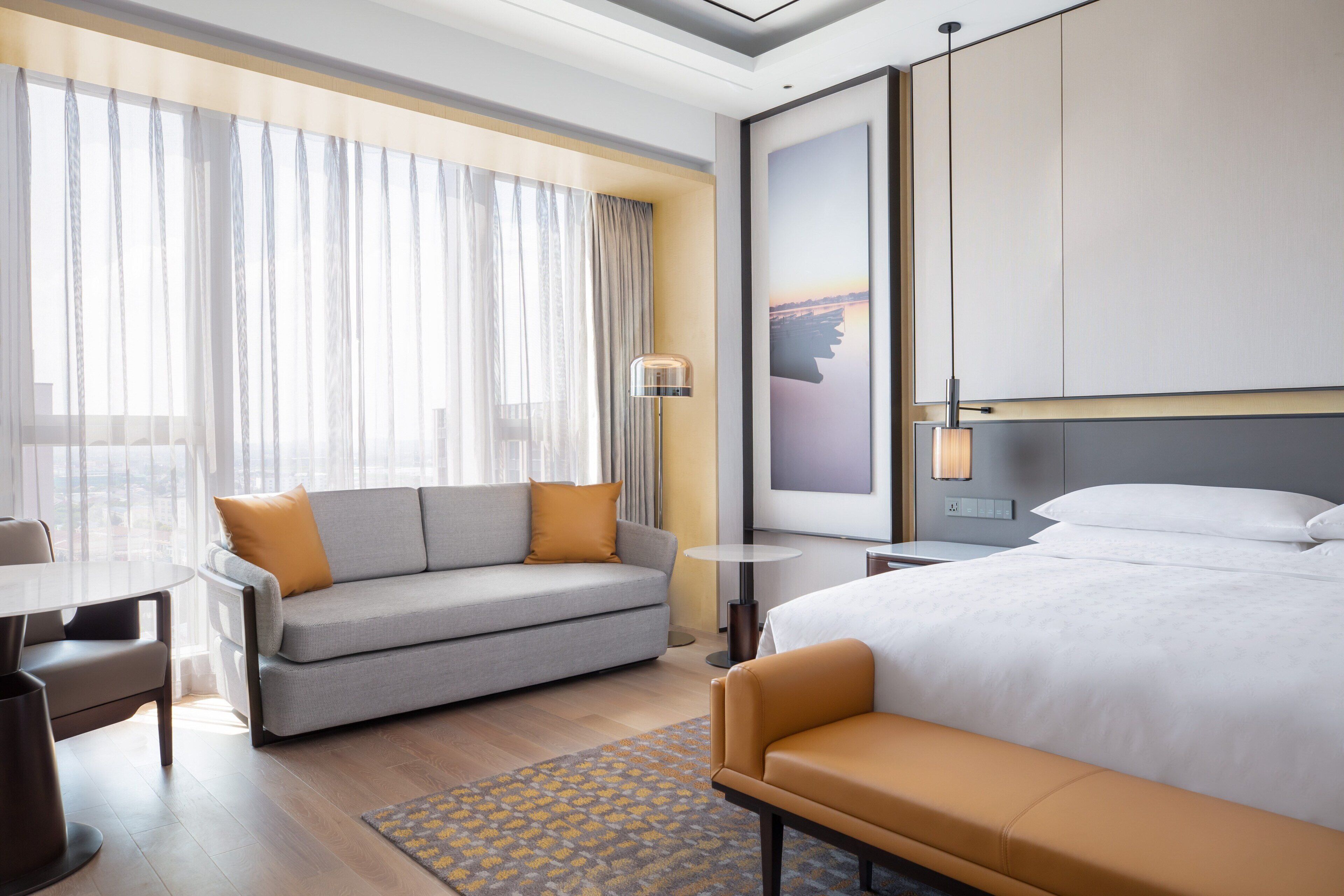 Et moderne hotelværelse med en stor seng, en sofa, et lille bord og et skrivebord.
