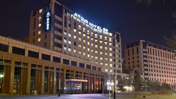 Un hotel de varios pisos con un letrero llamativo que dice "ATOUR HOTEL".