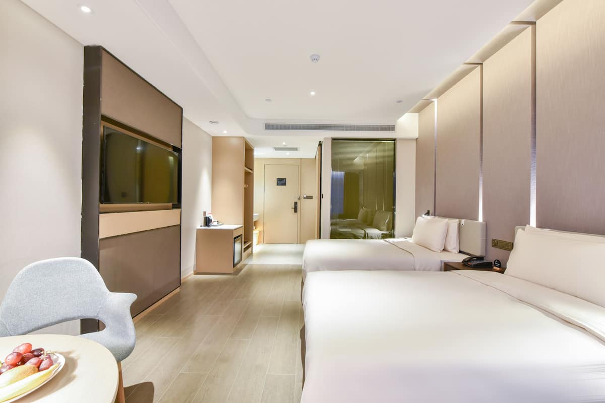 A modern hotel room with a bed, bedside table, and a seating area with a chair and a small table.