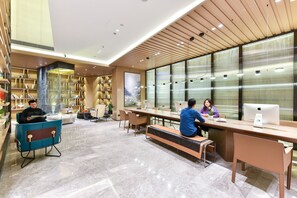 A modern library with bookshelves, a large window, and a seating area with tables and chairs.